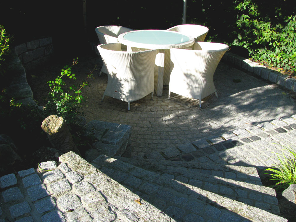 Terrasse mit weißen Gartenmöbel und Rundtisch